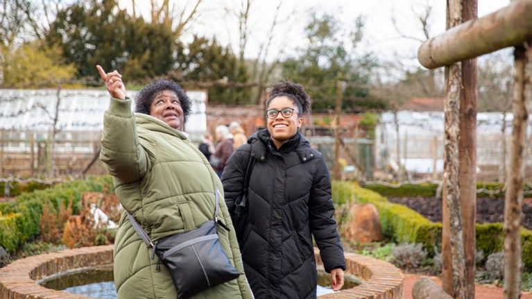 Two people in winter clothing looking at features in a garden